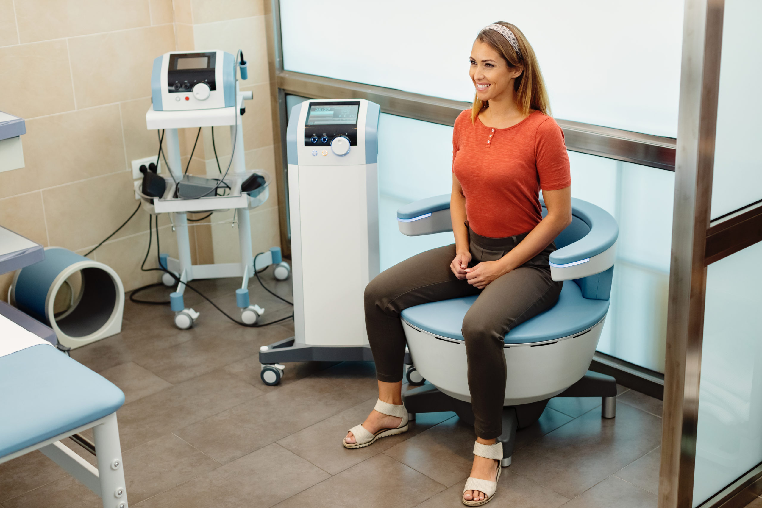 Young happy woman having non-invasive treatment for urinary incontinence at the clinic.